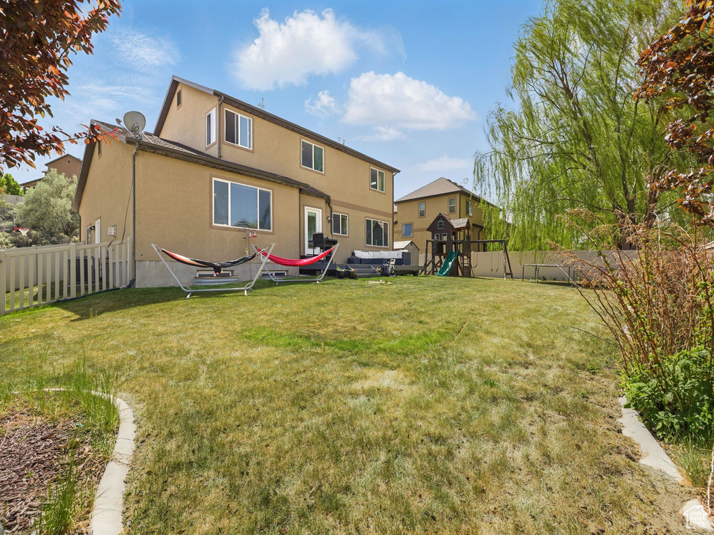 Rear view of property featuring a playground and stucco siding