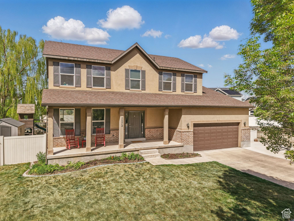 View of front of property with stucco siding, covered porch, concrete driveway, brick siding, and a garage