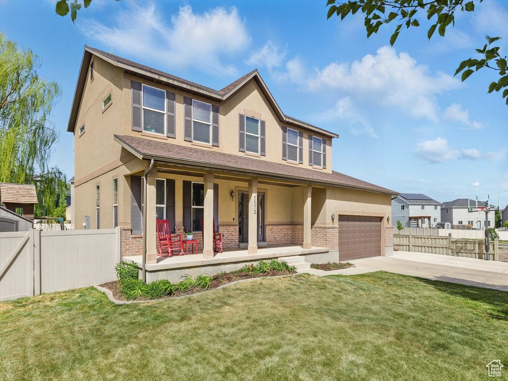View of front of property featuring covered porch, concrete driveway, stucco siding, a garage, and brick siding