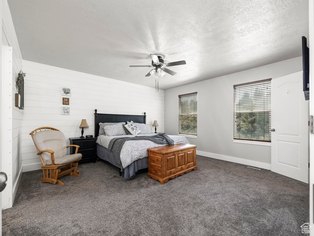 Bedroom featuring a textured ceiling, carpet flooring, baseboards, and a ceiling fan