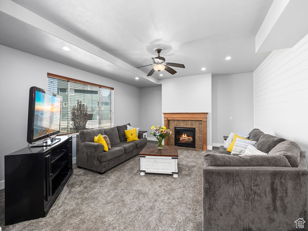Carpeted living room with recessed lighting, ceiling fan, a tiled fireplace, and baseboards