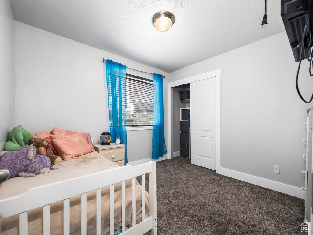 Bedroom featuring dark carpet, baseboards, and a closet