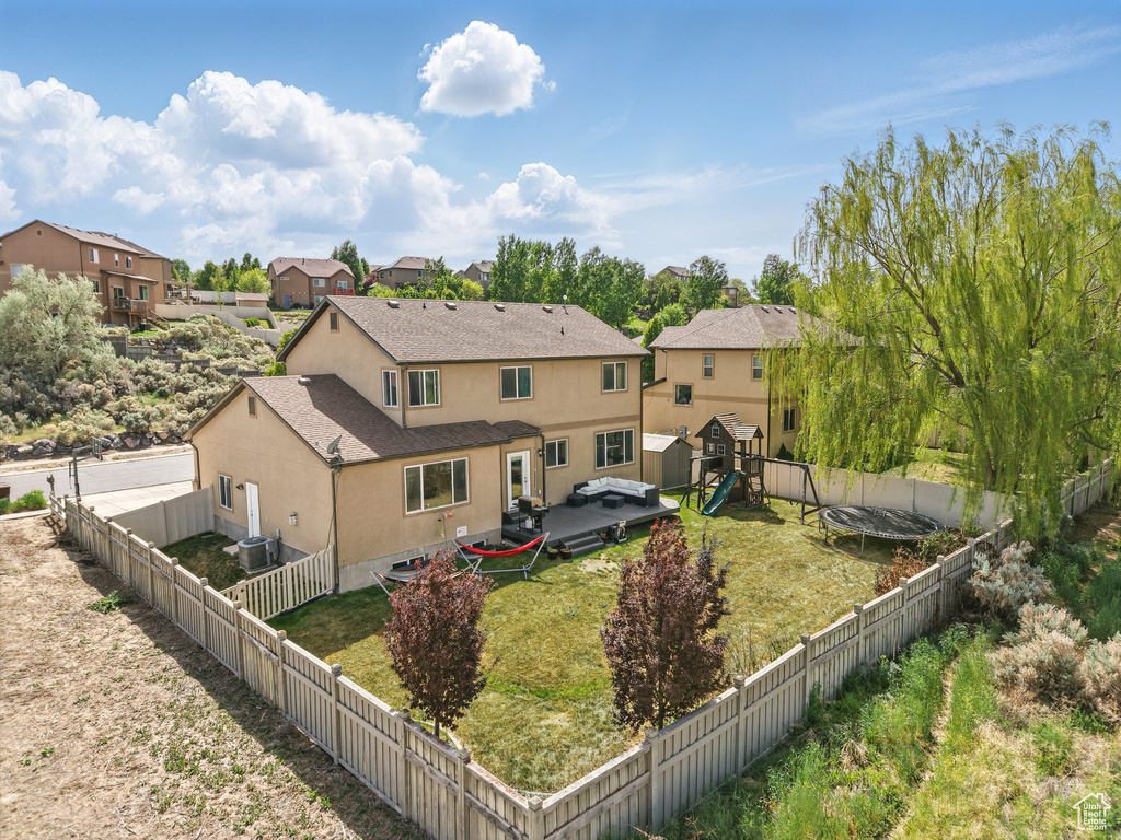 Back of property with stucco siding, a playground, a shingled roof, a residential view, and central AC unit