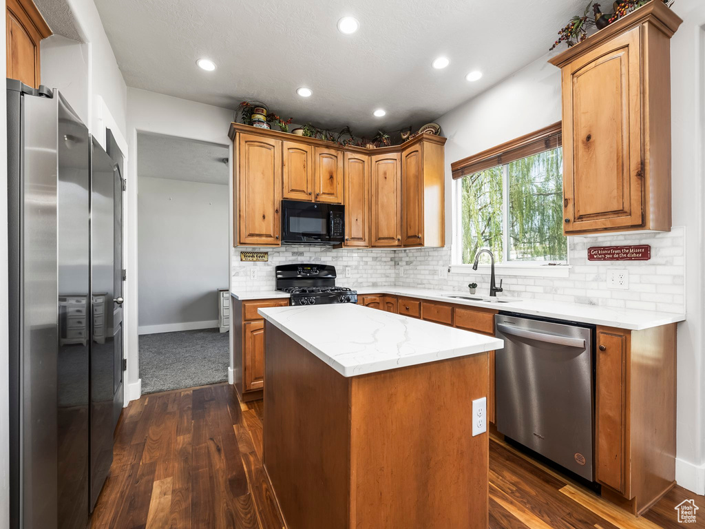 Kitchen with black appliances, a sink, dark wood finished floors, recessed lighting, and a center island