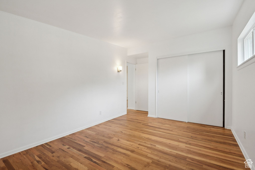 Unfurnished bedroom with light wood-style flooring, a closet, and baseboards