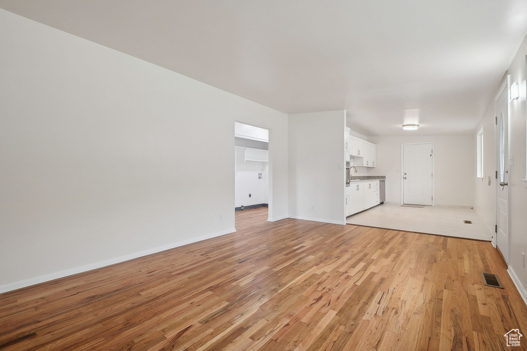 Unfurnished living room with light wood finished floors and baseboards