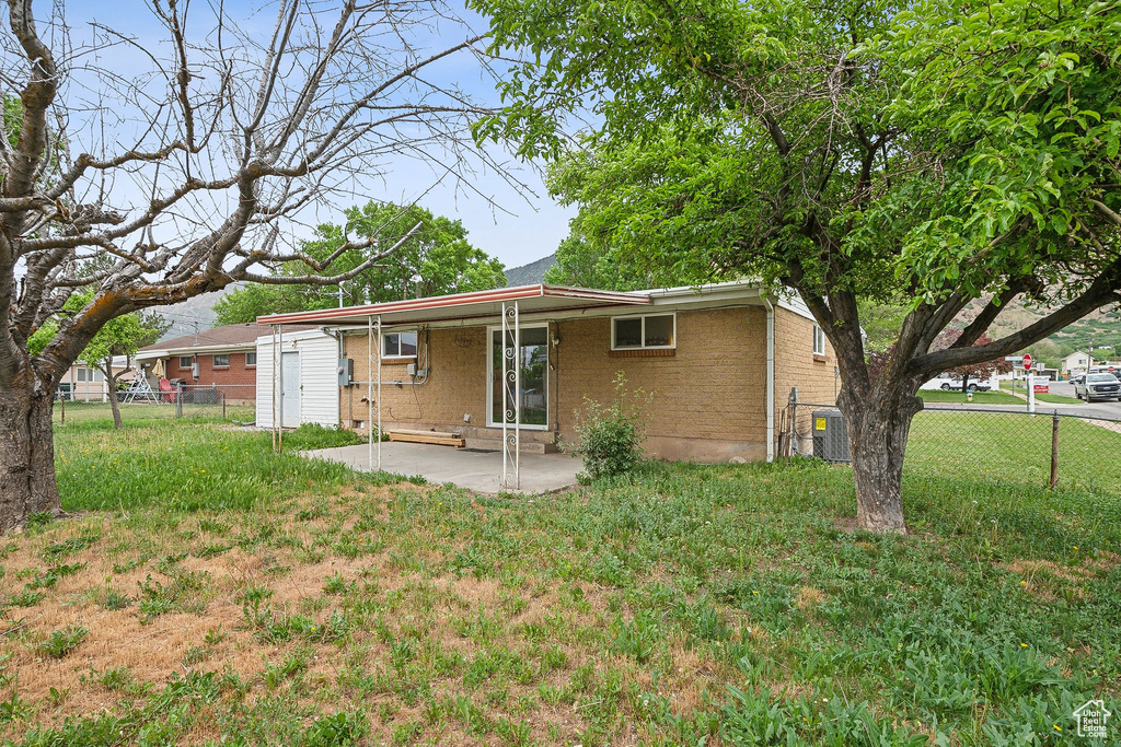 Back of property featuring a patio, brick siding, and central AC