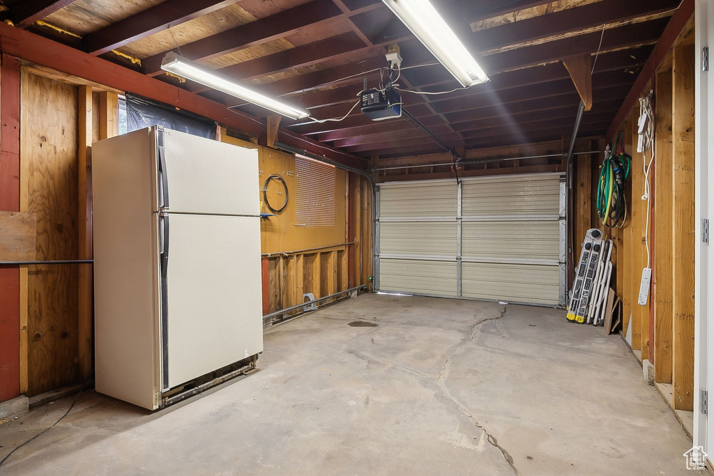 Garage featuring freestanding refrigerator and a garage door opener