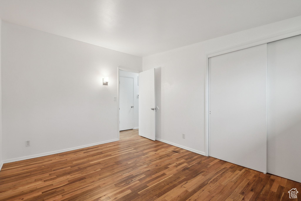 Unfurnished bedroom featuring wood finished floors, a closet, and baseboards