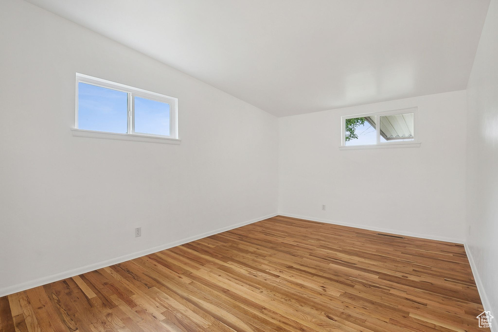 Empty room with light wood-type flooring, baseboards, and vaulted ceiling
