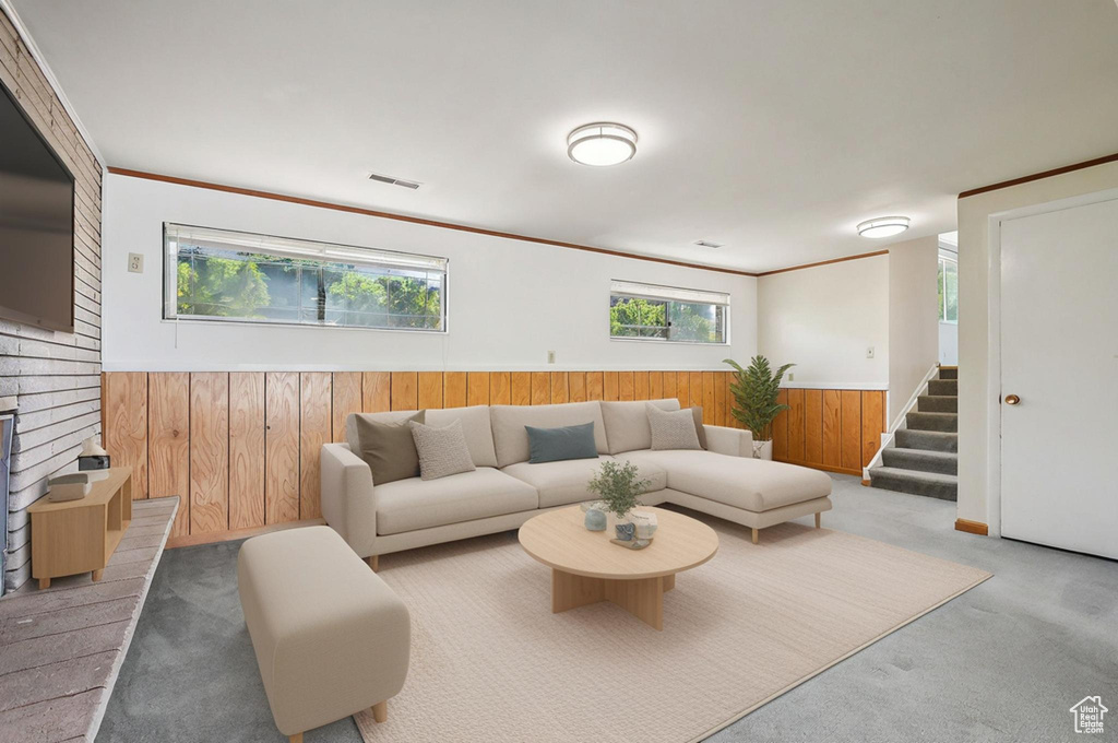 Carpeted living room featuring wooden walls, plenty of natural light, wainscoting, and stairs