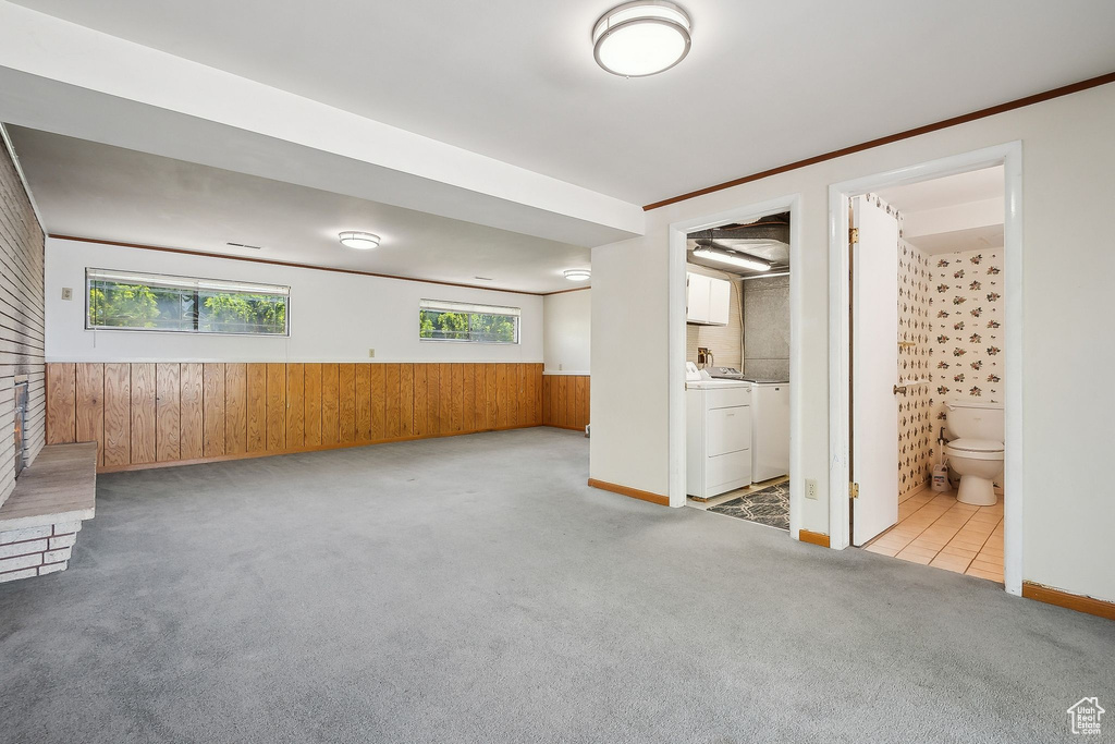 Unfurnished living room with wooden walls, carpet floors, healthy amount of natural light, independent washer and dryer, and a wainscoted wall