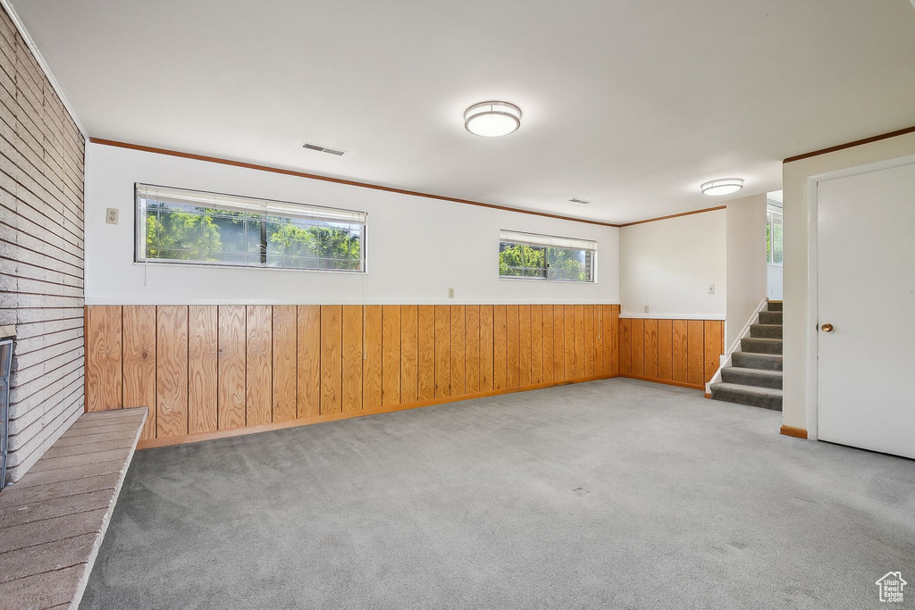 Unfurnished room with wood walls, stairs, carpet, wainscoting, and baseboards