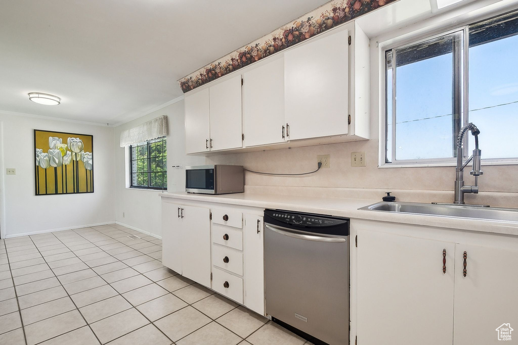 Kitchen with appliances with stainless steel finishes, a sink, light countertops, light tile patterned floors, and white cabinetry
