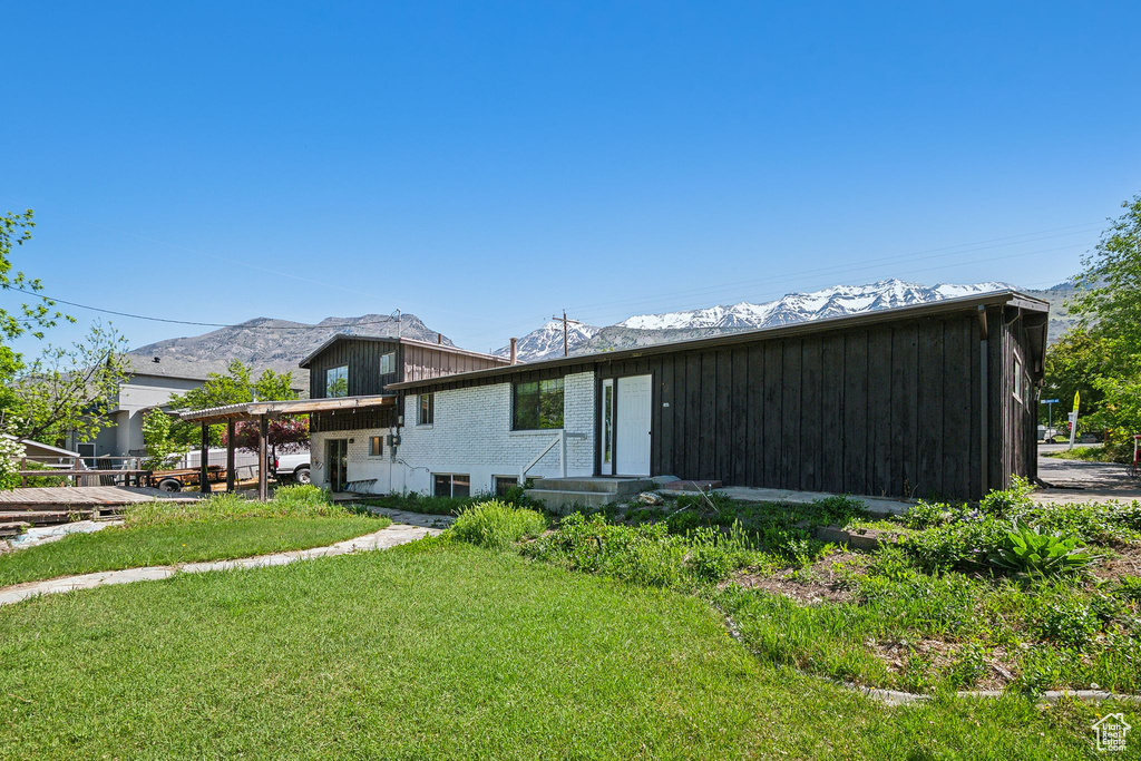 Rear view of house with a yard, a mountain view, and board and batten siding