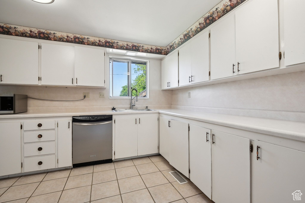 Kitchen featuring appliances with stainless steel finishes, a sink, white cabinets, and light countertops