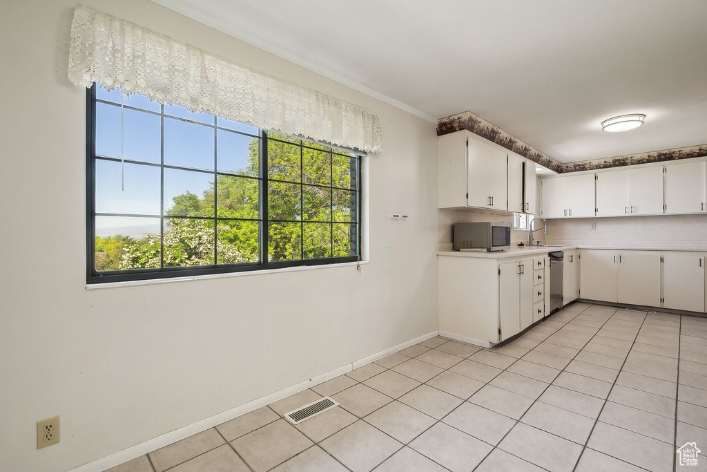 Kitchen featuring light countertops, plenty of natural light, stainless steel dishwasher, a sink, and crown molding
