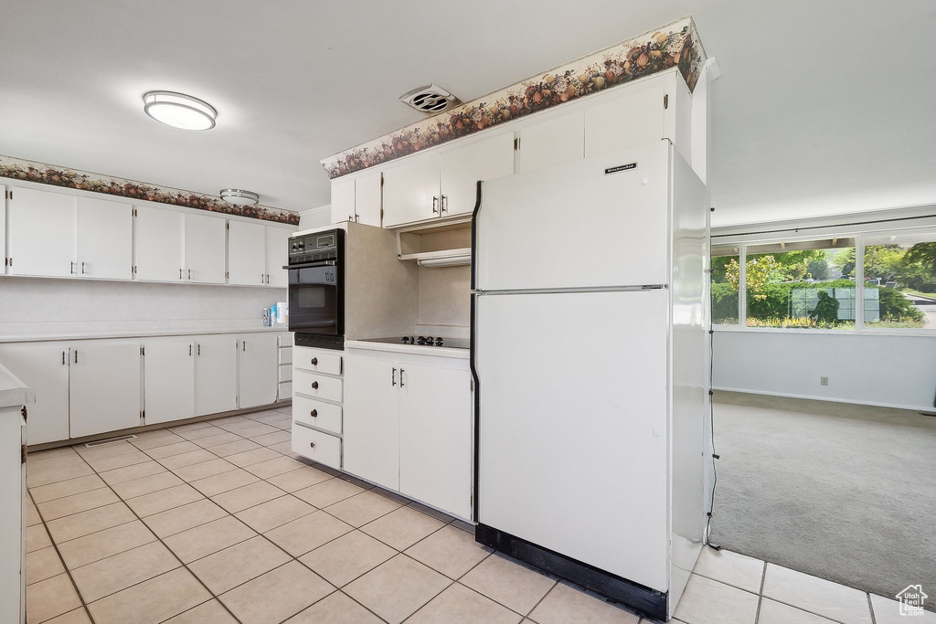 Kitchen featuring black appliances, light countertops, white cabinets, and light tile patterned floors