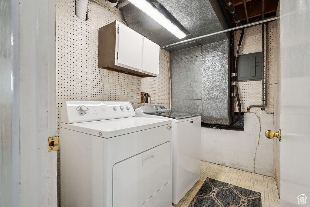 Washroom featuring cabinet space, washer and clothes dryer, and electric panel