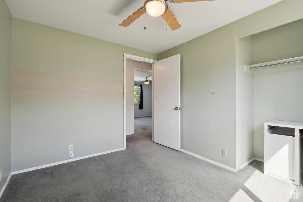 Unfurnished bedroom with carpet flooring, baseboards, a closet, and a ceiling fan