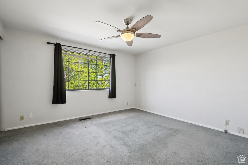 Carpeted empty room with ceiling fan and baseboards