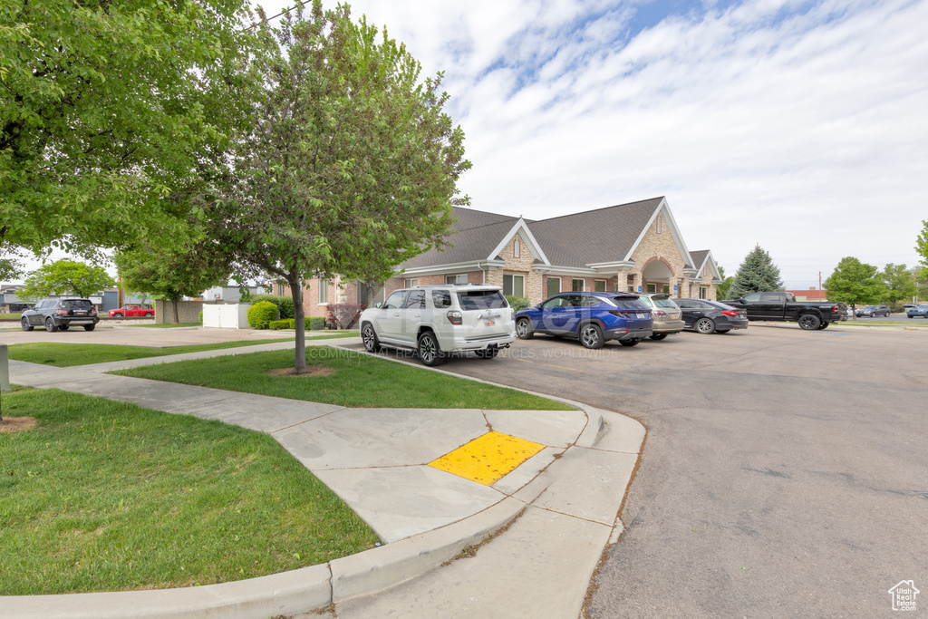 View of front of home with uncovered parking, brick siding, and a front yard