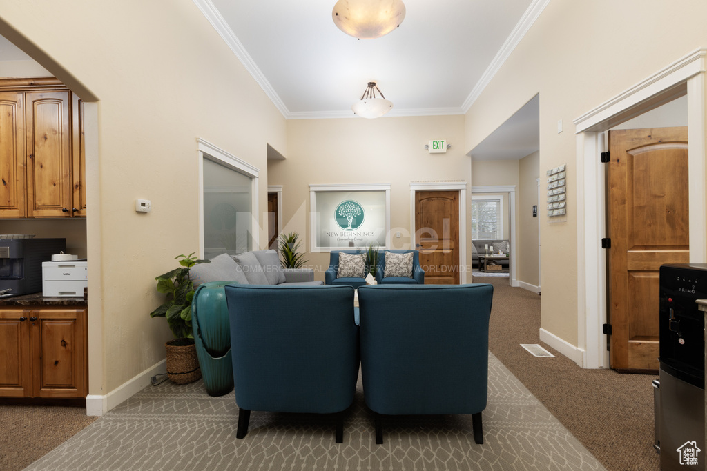 Carpeted living area with ornamental molding and baseboards