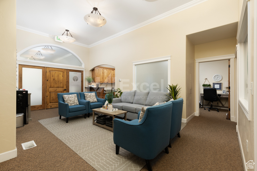 Living room featuring carpet floors, an office area, ornamental molding, baseboards, and arched walkways