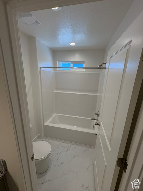 Bathroom featuring toilet, shower / washtub combination, marble finish floors, a textured ceiling, and recessed lighting