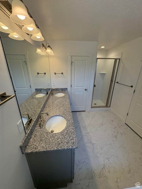 Full bathroom with double vanity, a shower stall, and marble finish floors