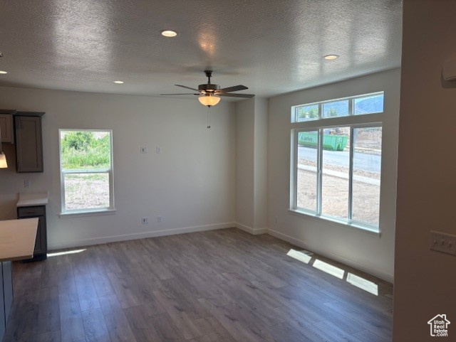 Unfurnished living room featuring a ceiling fan, dark wood-type flooring, a textured ceiling, recessed lighting, and baseboards