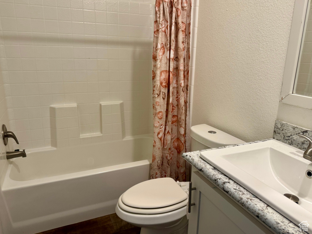 Full bath with toilet, a textured wall, shower / tub combo, and vanity