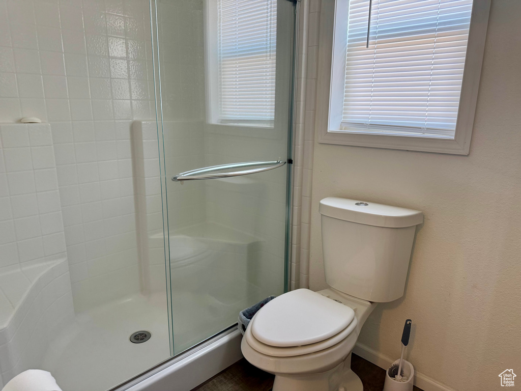 Bathroom featuring an enclosed shower, toilet, and baseboards