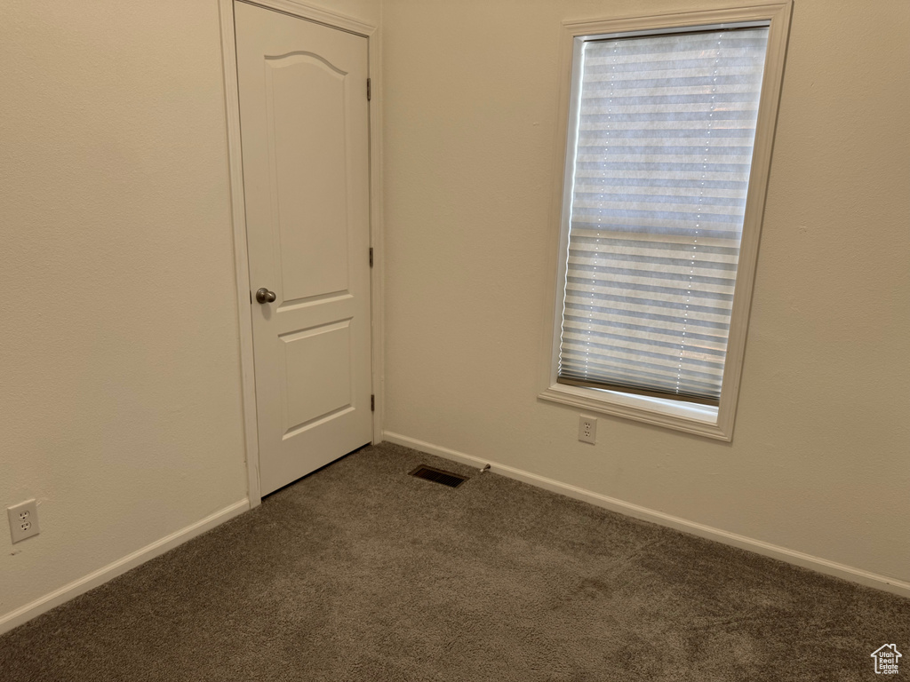 Unfurnished room with dark carpet and baseboards