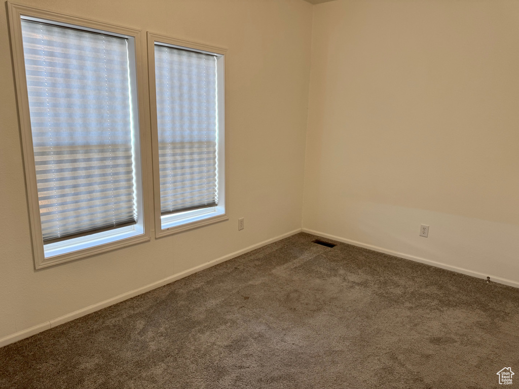 Unfurnished room featuring dark carpet and baseboards