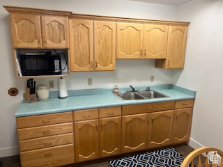 Kitchen with black microwave, a sink, light countertops, and baseboards