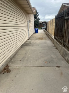 View of property exterior with fence, a patio, and driveway