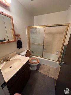 Bathroom featuring enclosed tub / shower combo, vanity, and toilet