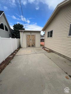 View of patio / terrace featuring a storage shed, fence, and an outdoor structure