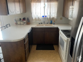 Kitchen featuring white appliances, a sink, light countertops, and a peninsula