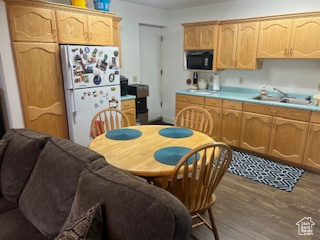 Kitchen featuring freestanding refrigerator, built in microwave, a sink, wood finished floors, and light countertops