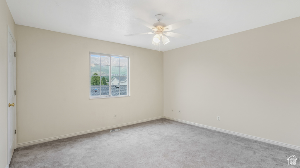 Carpeted empty room featuring ceiling fan and baseboards