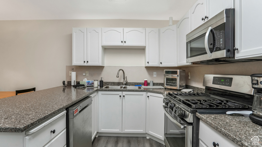 Kitchen with appliances with stainless steel finishes, a sink, and white cabinets