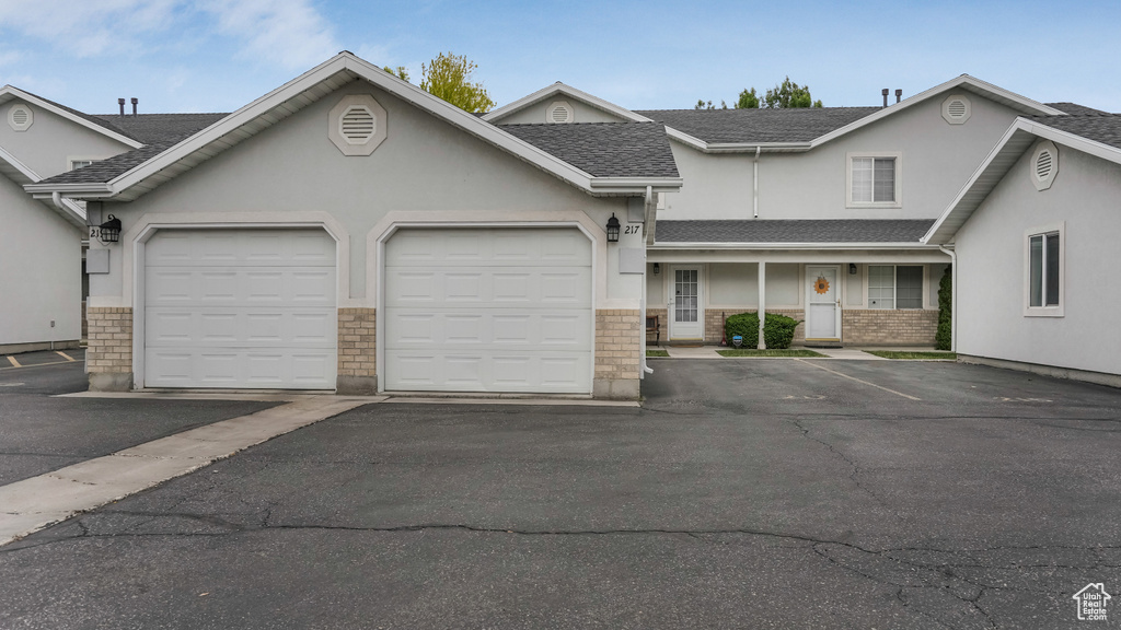 View of property featuring stucco siding, roof with shingles, and a garage