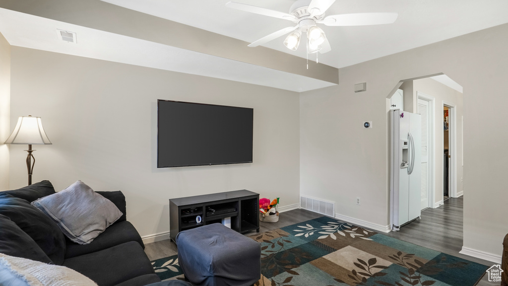 Living room with arched walkways, ceiling fan, and wood finished floors