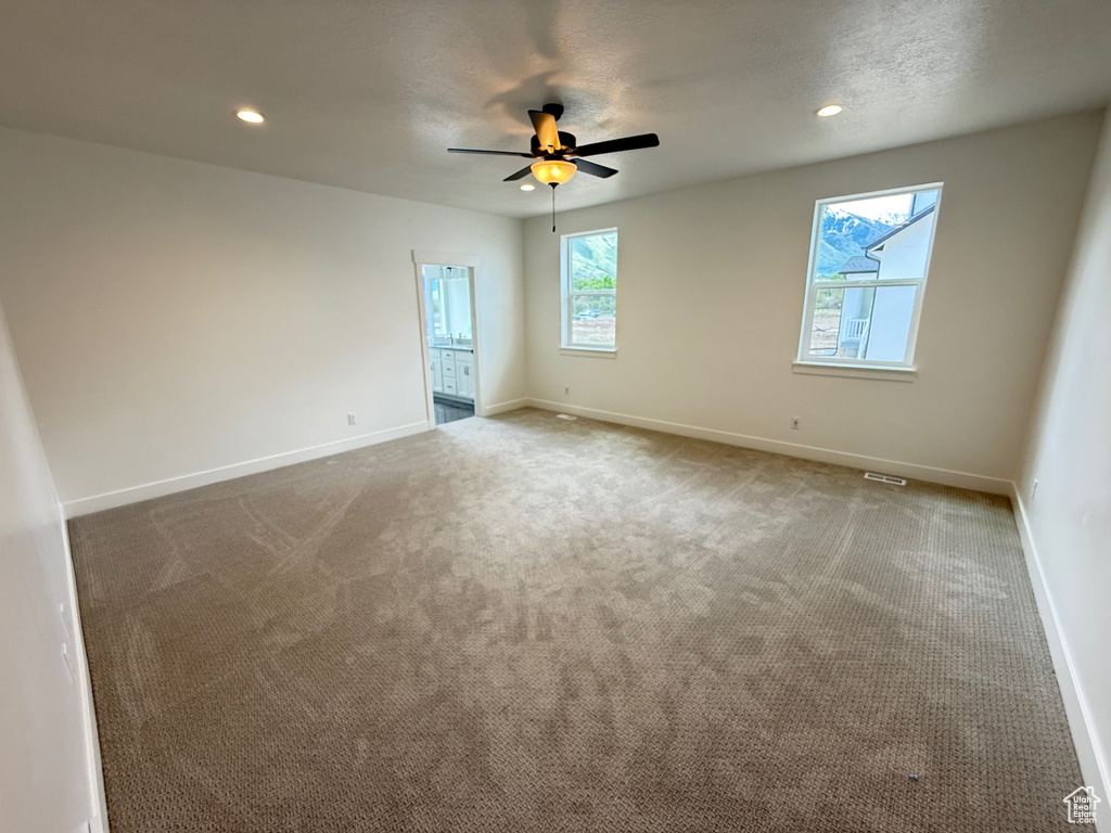 Carpeted spare room with ceiling fan, baseboards, and recessed lighting