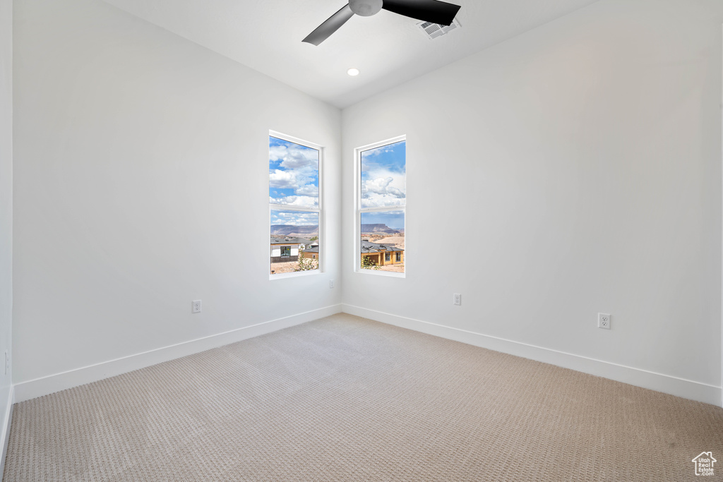 Spare room with ceiling fan, light carpet, and baseboards