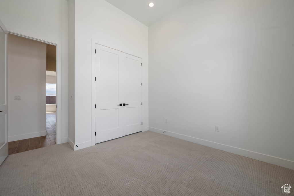 Unfurnished bedroom featuring light colored carpet, baseboards, recessed lighting, and a closet