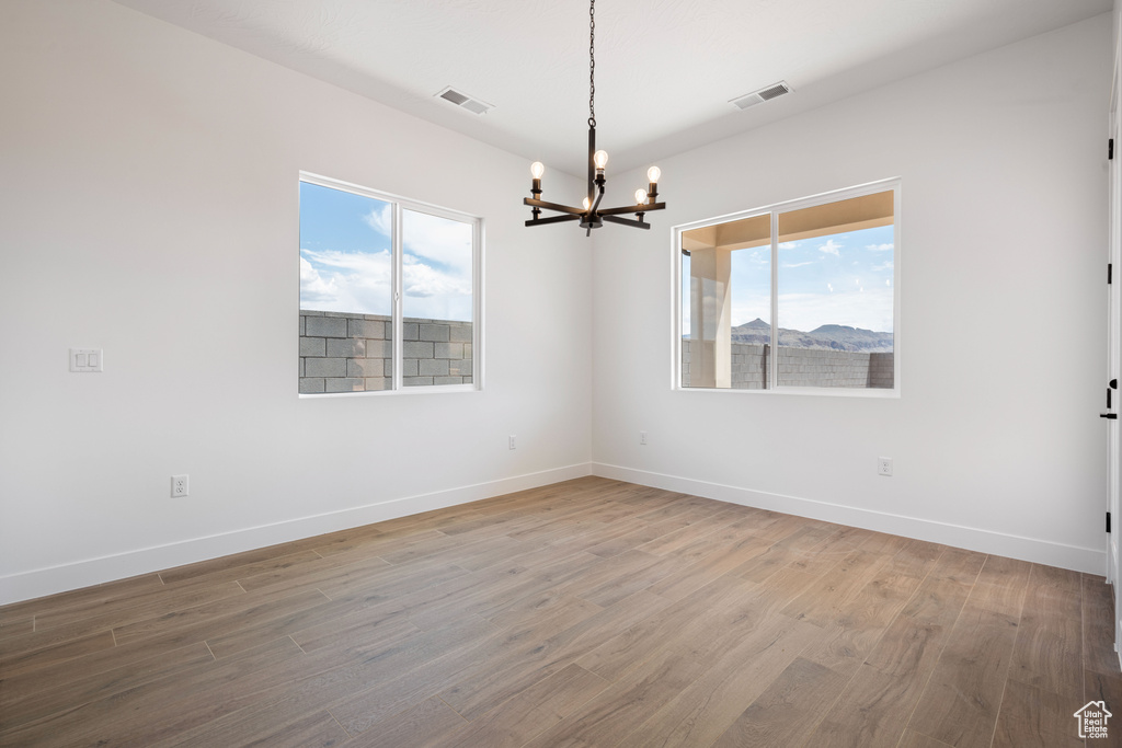 Spare room with a chandelier, wood finished floors, and baseboards