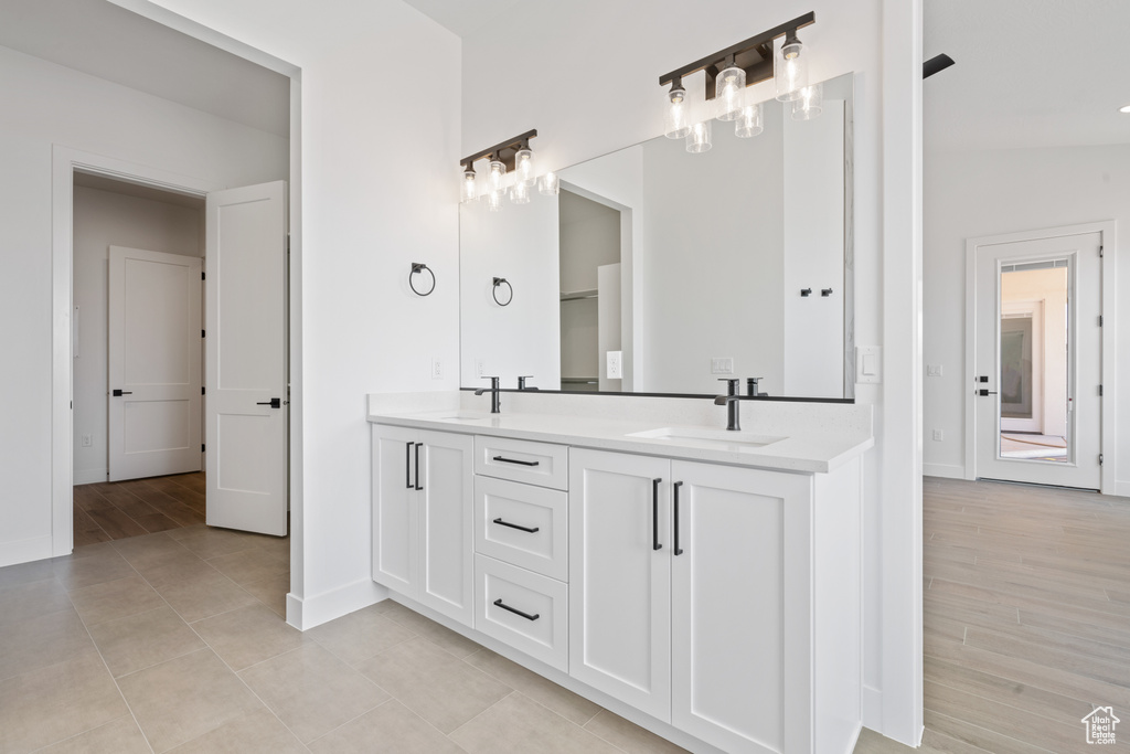 Bathroom with double vanity, baseboards, and tile patterned flooring